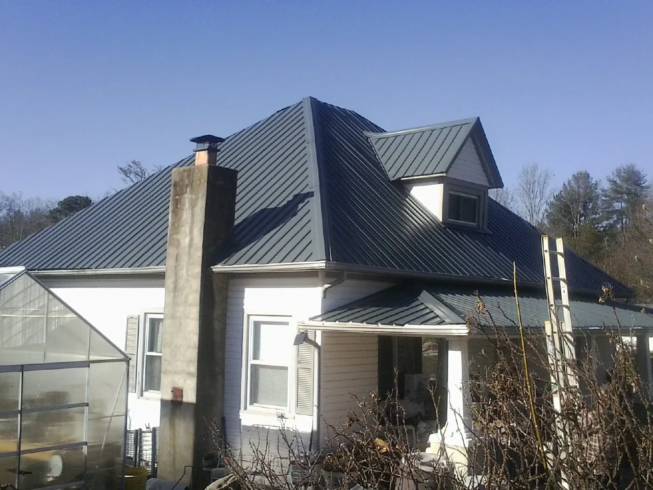 Dark blue standing seam metal roof on a white farmhouse with dormer — Slate & Tile Roof Repair by Roofing Brothers in Paeonian Springs