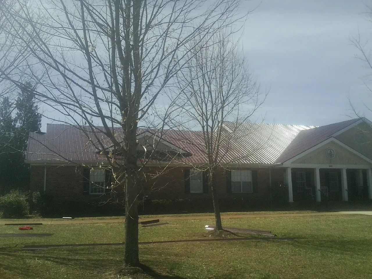 Red metal roof on a brick building seen from the front lawn in Paeonian Springs