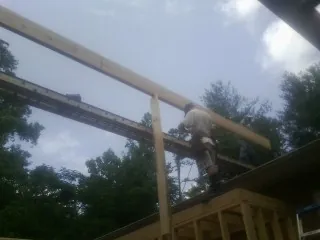 Carpenter setting a ridge beam over a new addition frame — Ice Dam Removal by Roofing Brothers in Paeonian Springs