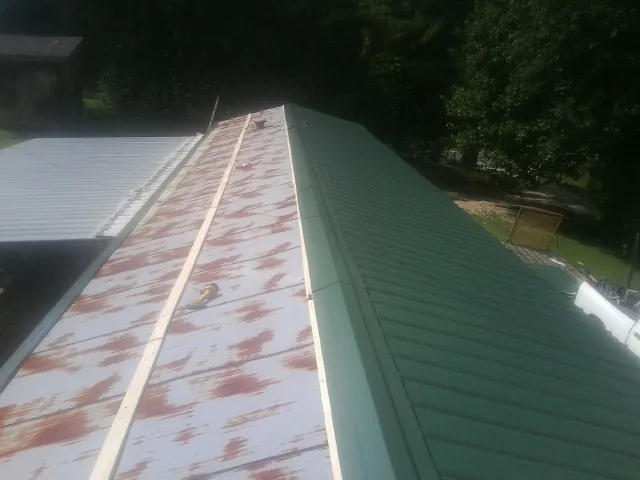 Old rusted panels beside newly installed green metal roofing — Wind Damage Roof Repair by Roofing Brothers in Paeonian Springs