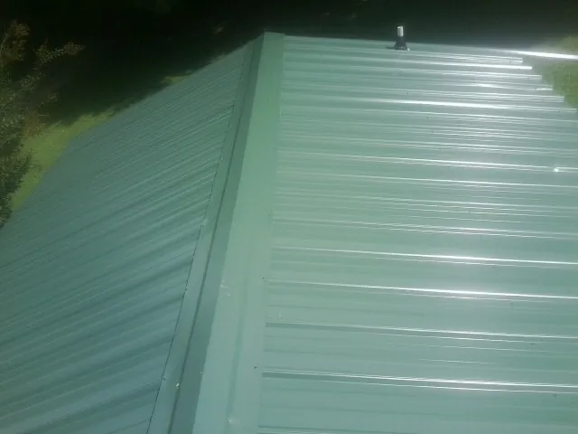 New green metal panels meeting at the ridge of a roof — Flat Roof Repair work by our crew in Paeonian Springs