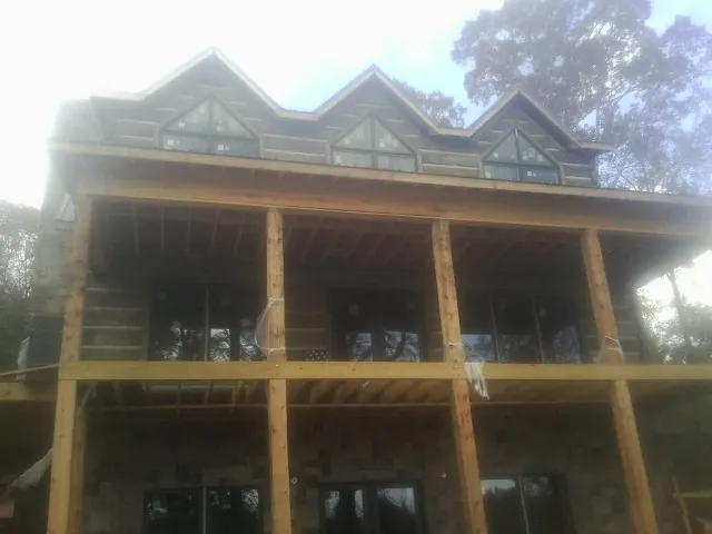 Dormers and porch framing on a large log home under construction — Roof Coating work by our crew in Paeonian Springs