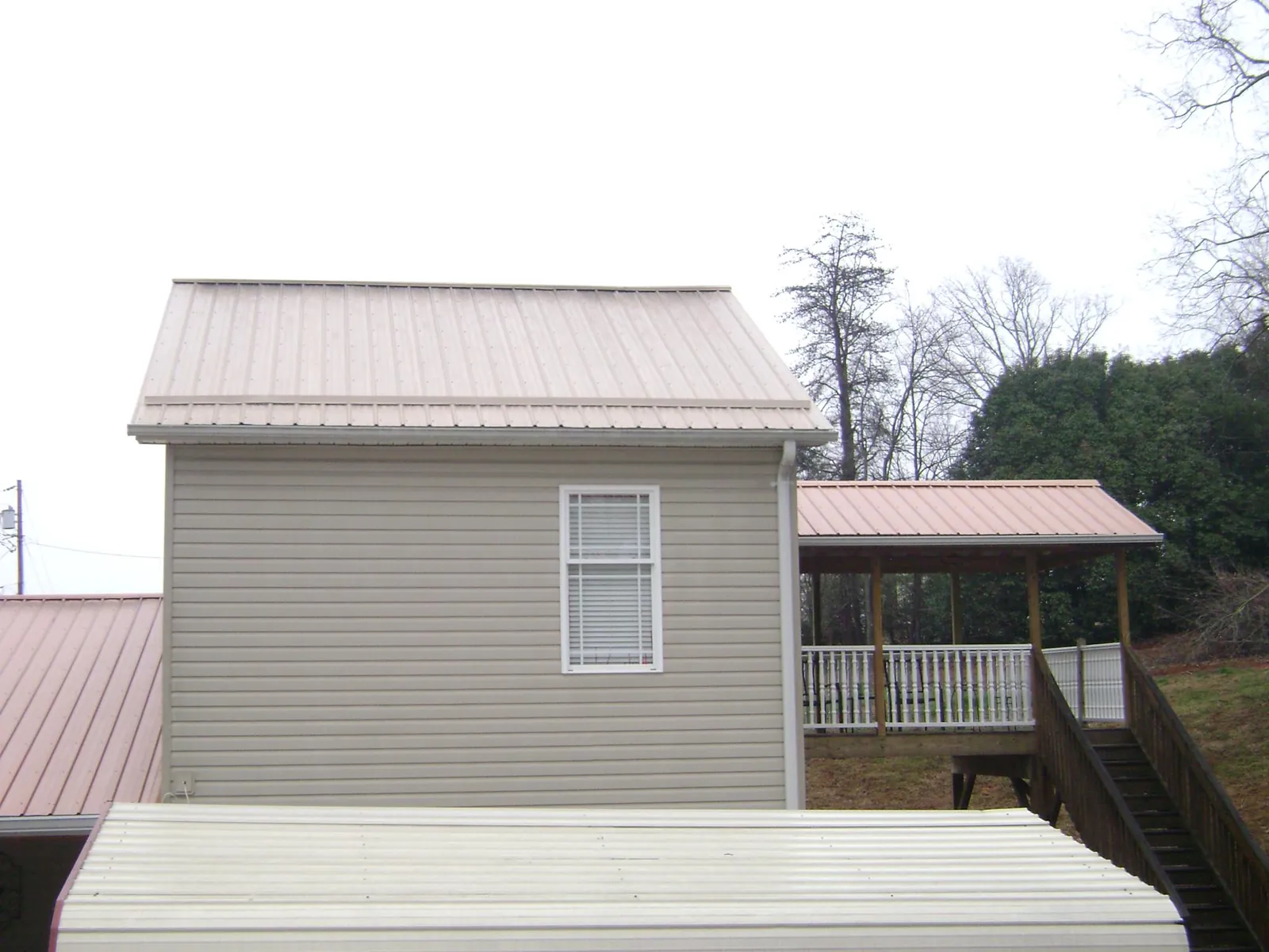Tan metal roofs on a two story addition and attached porch, from a Roof Replacement job in Paeonian Springs