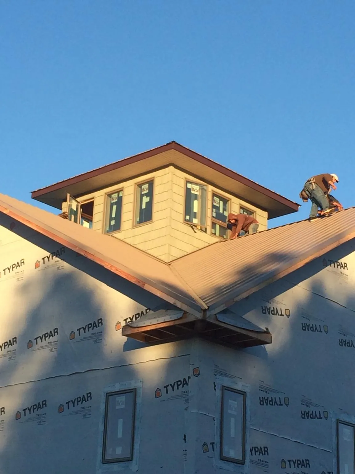 Roofers working around a rooftop cupola on a new metal roof at sunset — Roof Waterproofing in Paeonian Springs by Roofing Brothers